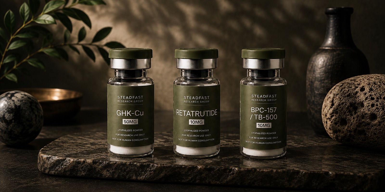 Steadfast GHK-Cu, Retatrutide, and BPC-157/TB-500 vials staged on a stone slab